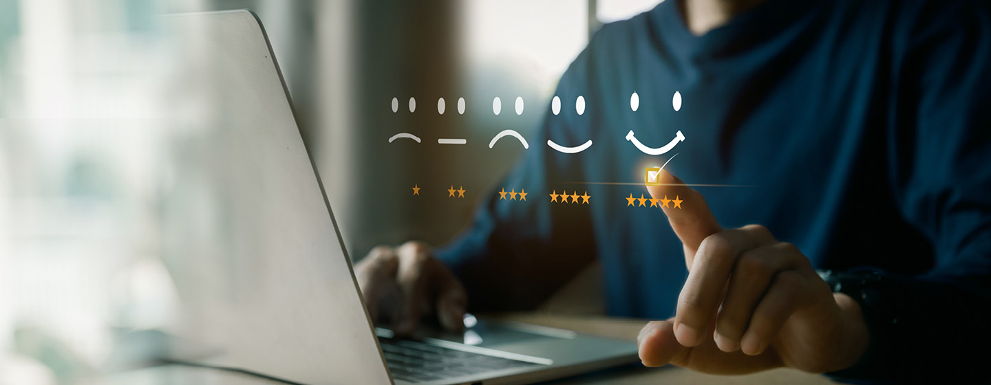 Close-up of computer and a scale of smileys referring to 1-5 stars customer satisfaction